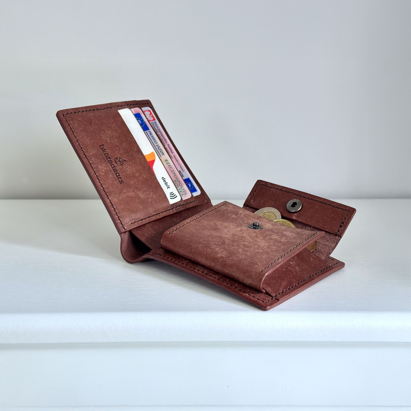 Portfel posiada łącznie 7 kieszonek, 3 przeznaczone na karty, 2 na dodatkowe na karty, wizytówki, złożone banknoty lub drobne notatki, tradycyjną przegródkę na banknoty oraz dużą kieszonkę na monety zamykaną na zatrzask 😊

#portfel #skorzanyportfel
#skoranaturalna #skoragarbowanaroslinnie
#skora #galanteriaskorzana #kaletnictwo #kaletnik
#rzemiosło #rękodzielo #wykonanerecznie
#pomyslnaprezent
#wallet #leatherwallet #bifoldwallet
#leatherwork #leathercraft #leathergoods
#leather #naturalleather #vegetabletannedleather
#handcrafted #handmade #handstitched
#edc #everydaycarry